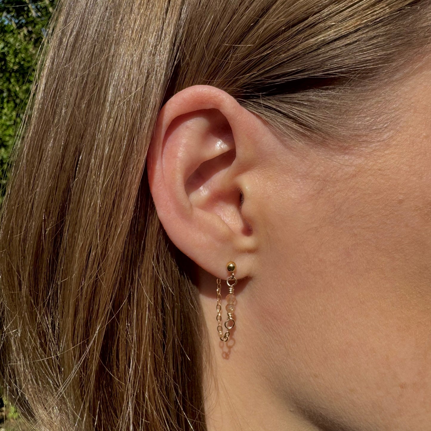 Close up of gold filled chain and gemstone drop earrings on model