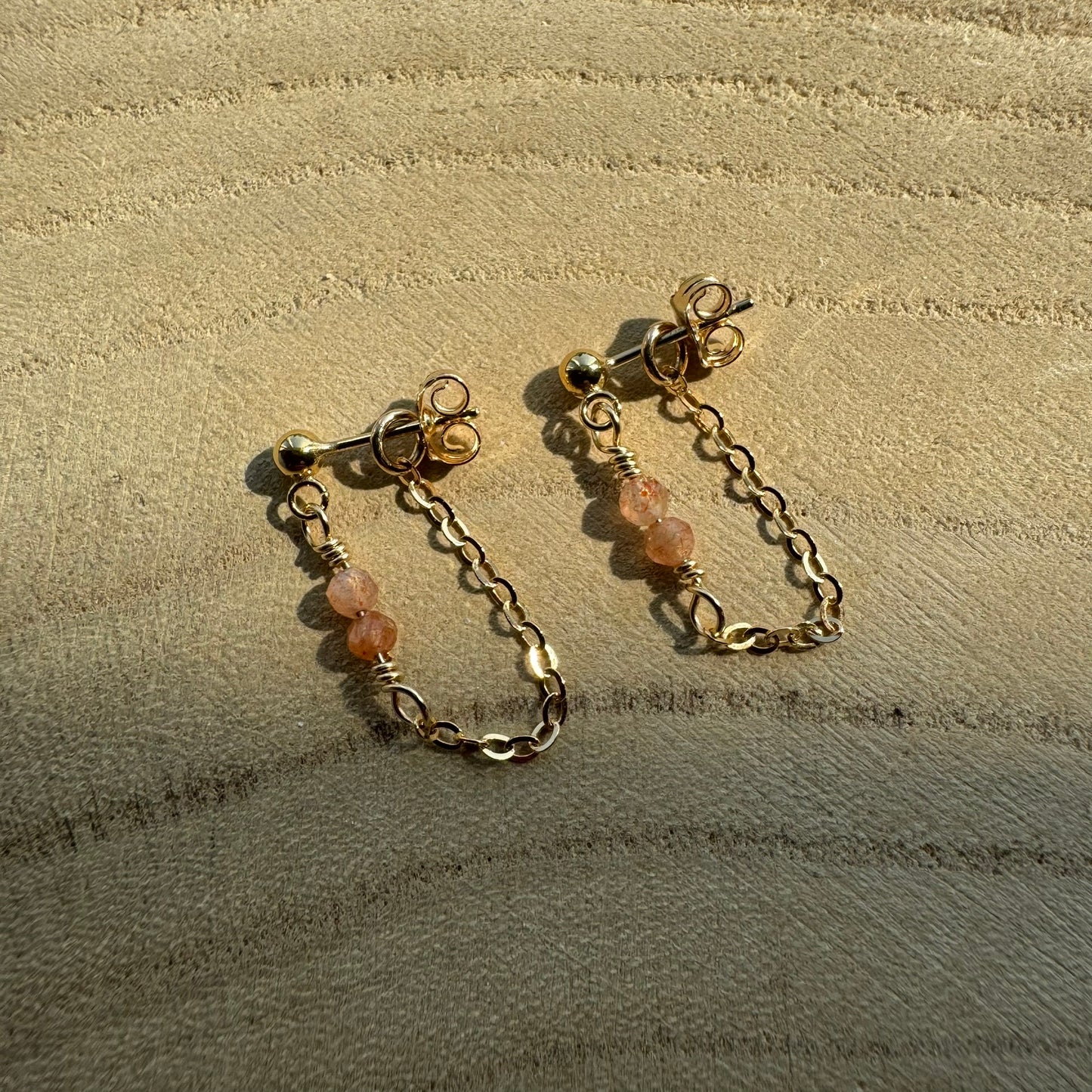 Gold filled chain and gemstone drop earrings on wooden surface