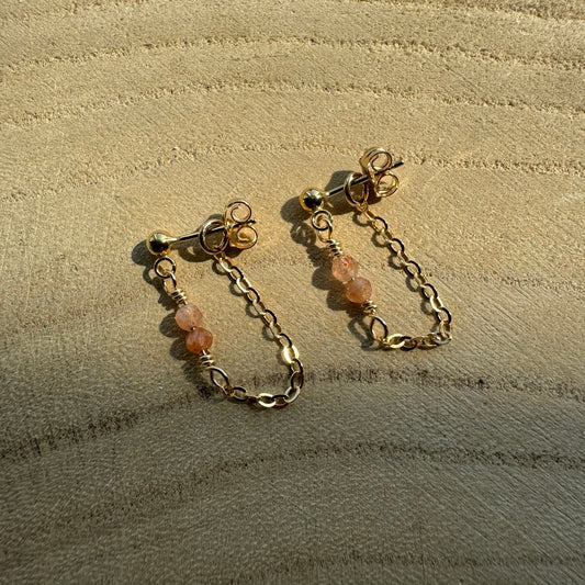 Gold filled chain and gemstone drop earrings on wooden surface