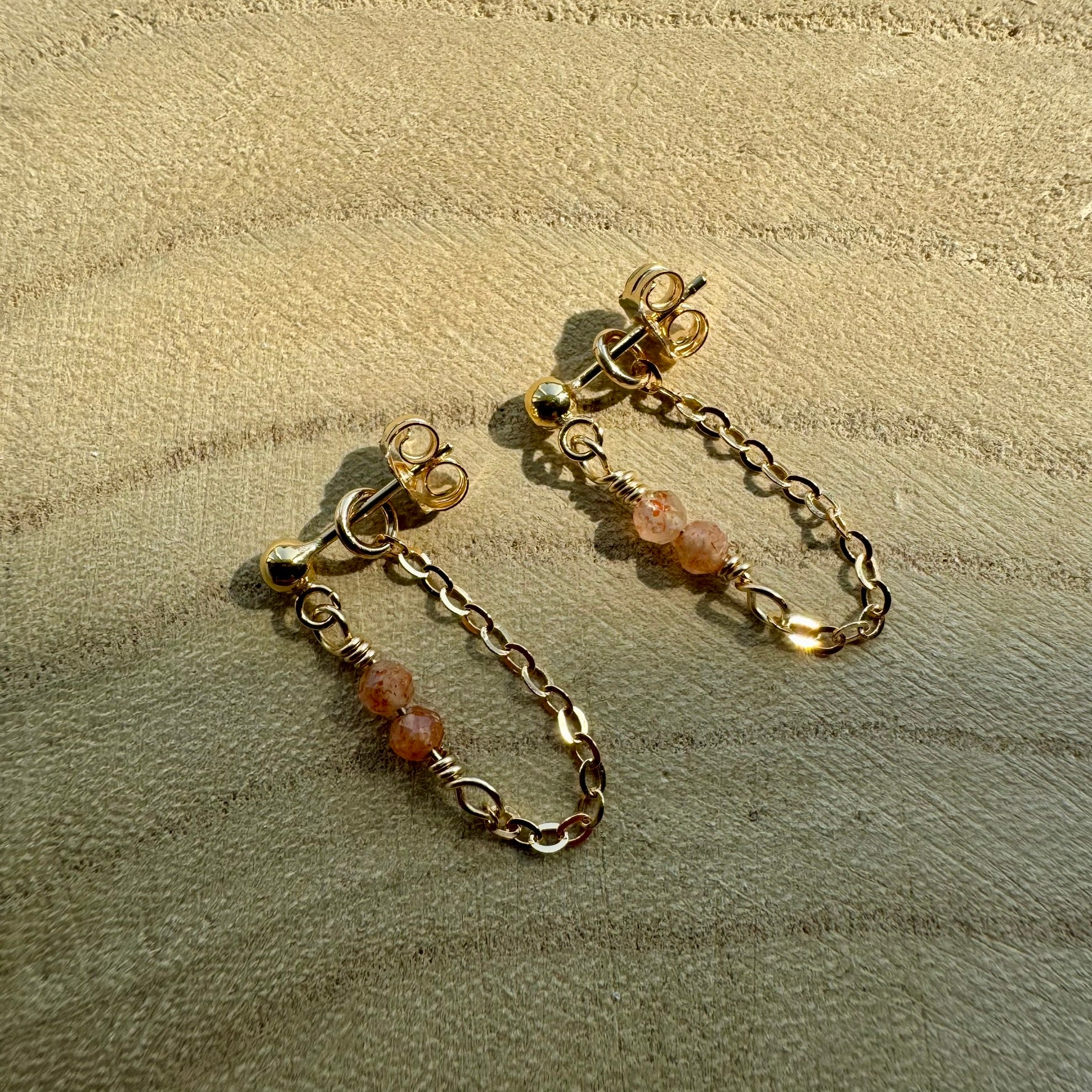 Gold filled chain and gemstone drop earrings on wooden surface