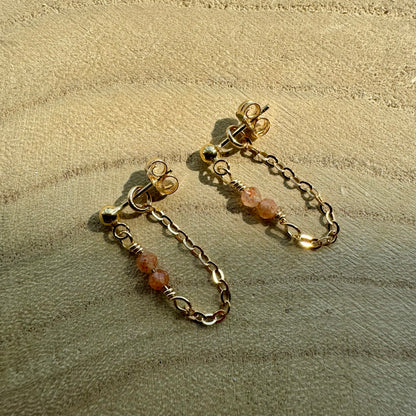 Gold filled chain and gemstone drop earrings on wooden surface