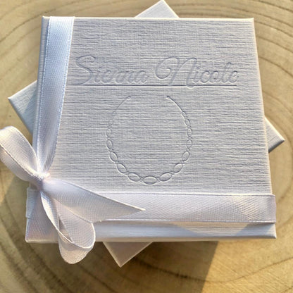 White box with 'Sienna Nicole' branding and a white ribbon on a wooden surface