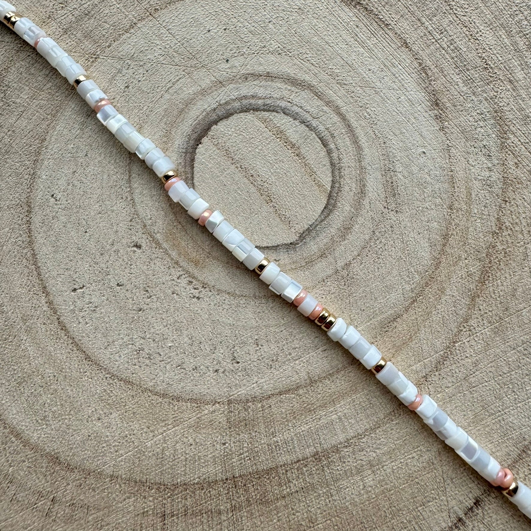 Close-up of handmade mother of pearl and peach seed bead gold filled bracelet