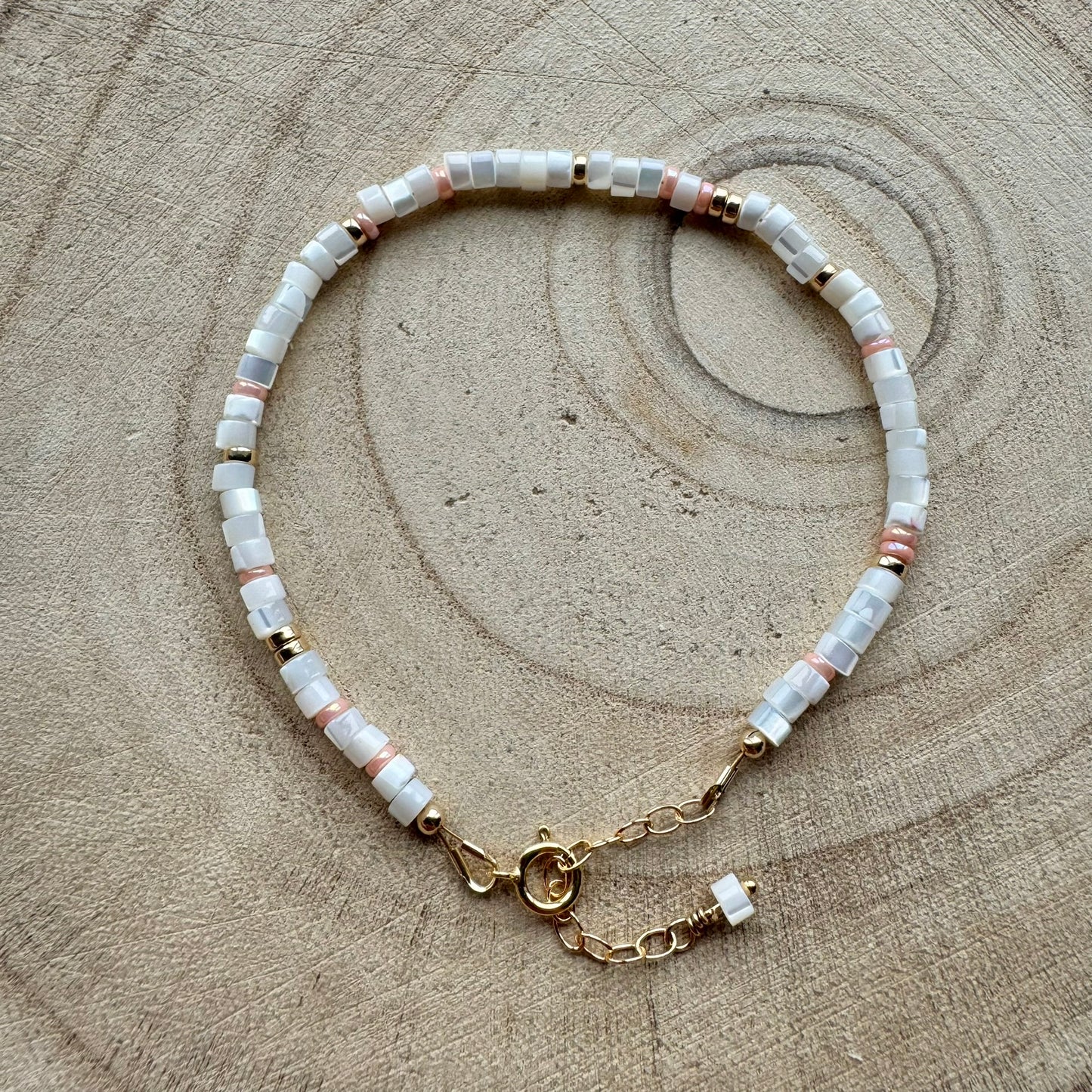Mother of pearl and gold filled bracelet on a wooden background
