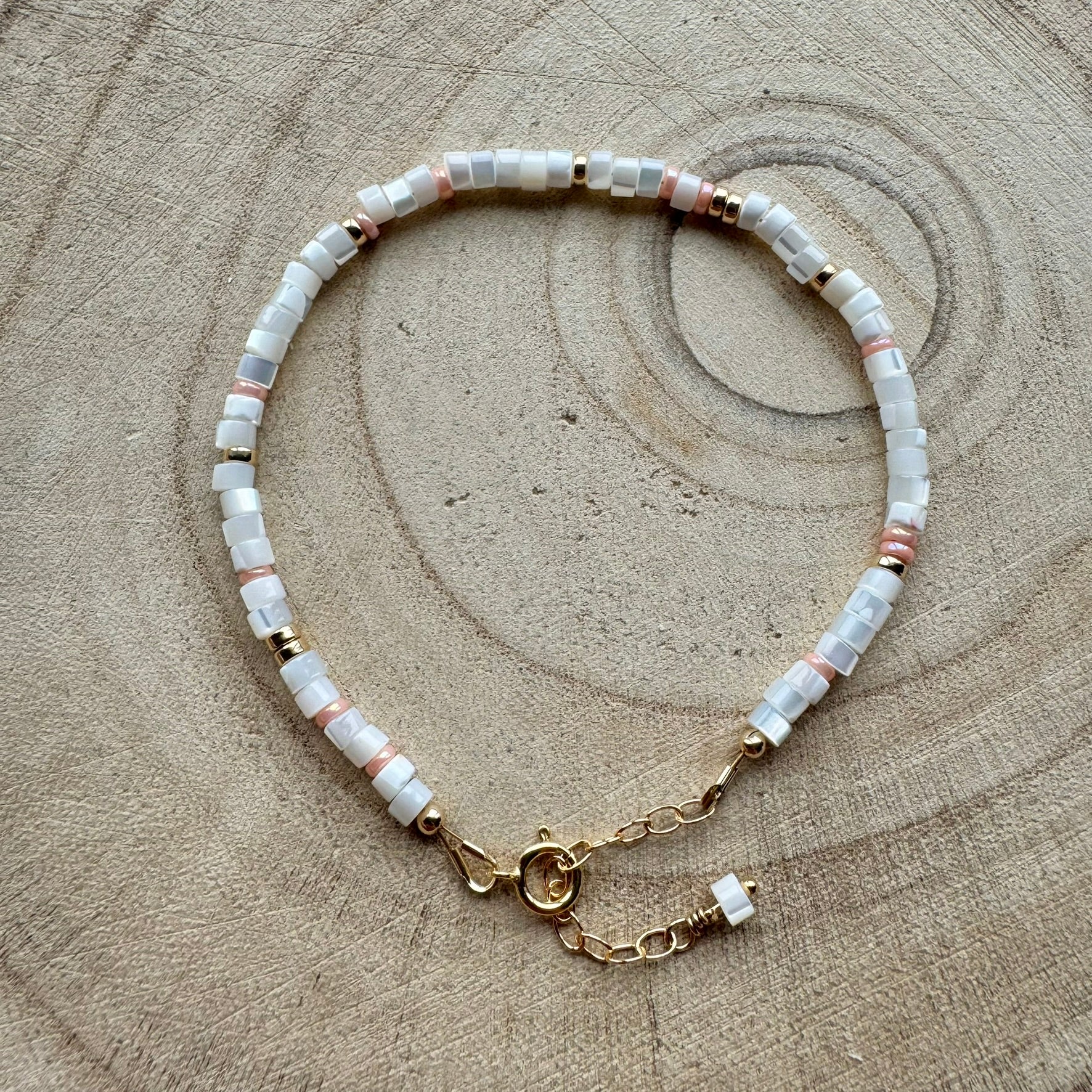 Mother of pearl and gold filled bracelet on a wooden background