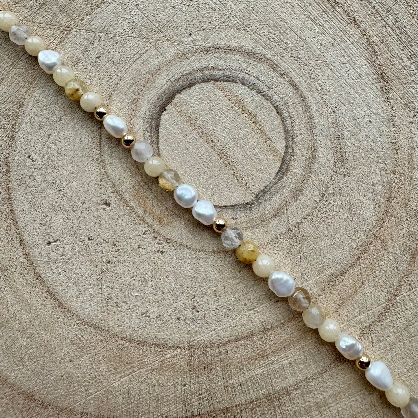 Pearl and mixed gemstone bracelet with gold filled details on wooden surface
