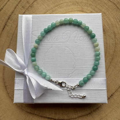 Blue green gemstone beaded bracelet on a white branded box with a white ribbon