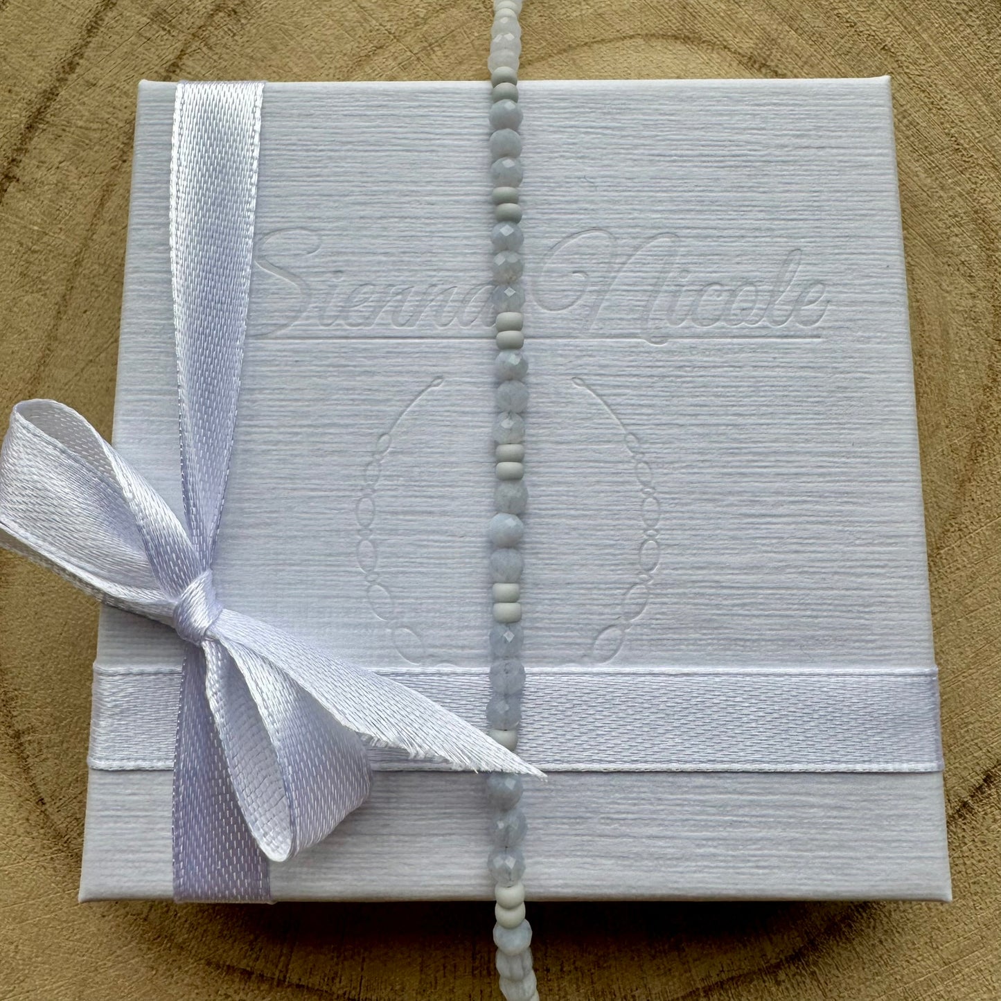 Vertical view of pale blue gemstone beaded bracelet on gift packaging