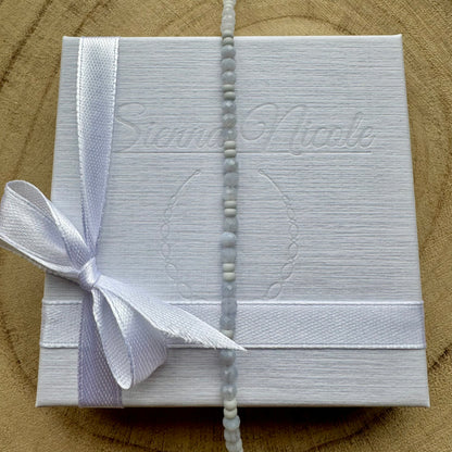 Vertical view of pale blue gemstone beaded bracelet on gift packaging