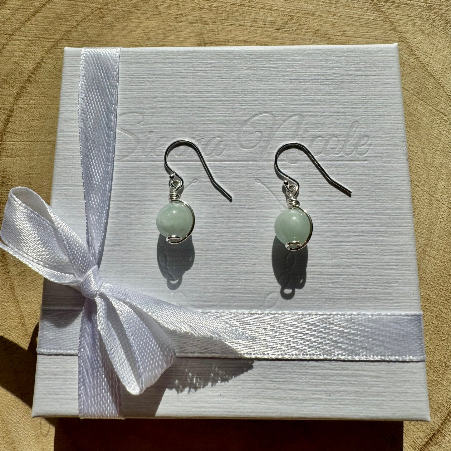 Pair of sterling silver drop gemstone earrings on a white box with a ribbon.