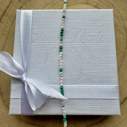 Vertical view of a mother of pearl and turquoise bracelet on gift packaging