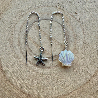 Silver threader earrings with starfish and shell charms on a wooden background