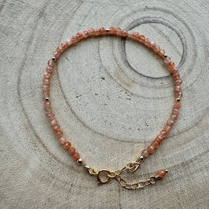 Peach sunstone bracelet with gold filled details on wooden surface