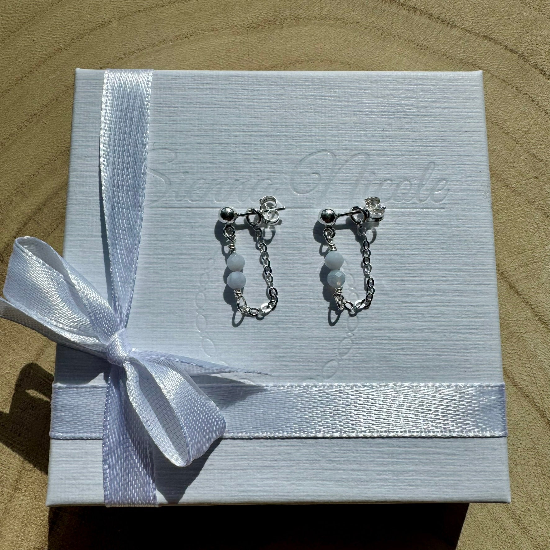 Pair of sterling silver chain earrings with blue chalcedony beads on gift packaging